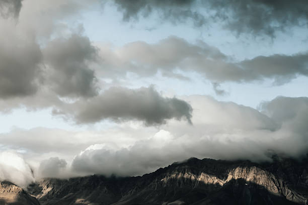 A view of a mountain peak near Kabul, Afghanistan. White, fluffy clouds in blue sky. A storm is coming.