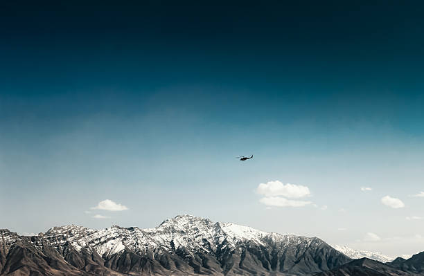 Coalition helicopter over snowy Afghanistan Mountains. Helicopter in Afghanistan as part of the NATO Training Mission Afghanistan (NTM-A) Kabul mountains are in the background