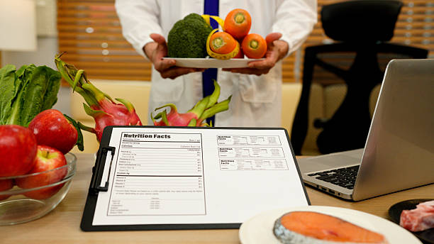 istock close up nutritionist holding a fresh vegetable while stand at desk with vegetables and fruits. Healthy food and diet planning concept 2248553067