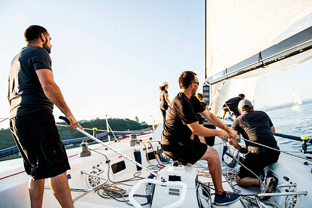 Two sailing crew members working rigging on sail boat with lens fare