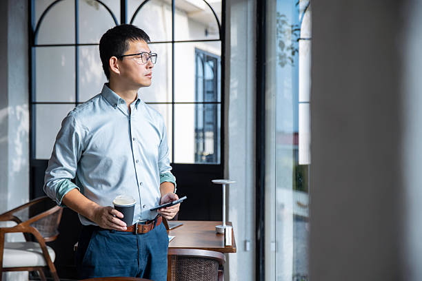 istock An Asian businessman is using his mobile phone at the window. 2248553414