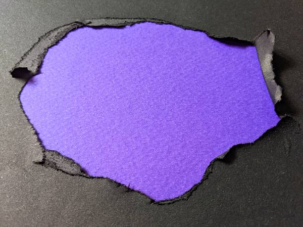 A bright purple sheet peeks through torn black paper, creating a striking contrast perfect for announcements, creative design or concept imagery. Ideal for themes of reveal, surprise and modern style