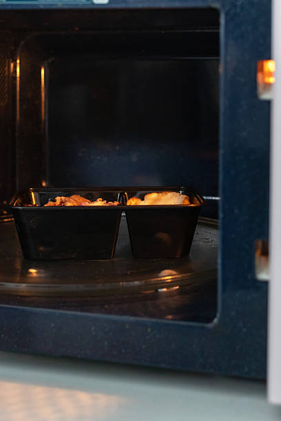 istock Meal tray in microwave warming with roasted chicken and side in black container creating cozy kitchen scene 2248554439