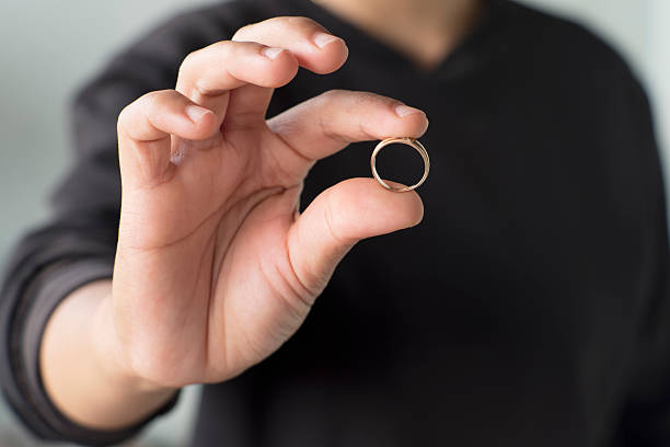 istock Hand Holding Gold Ring Close-Up on Neutral Background 2248556007