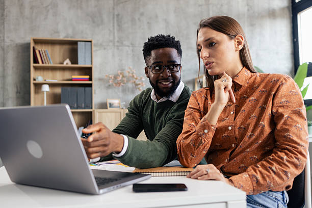 istock Colleagues collaborating on laptop, discussing business strategy in office 2248556370