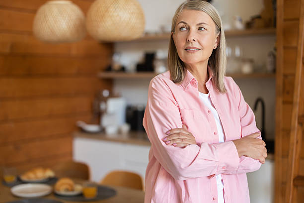 istock Mature woman standing in kitchen area with friendly smile 2248557742