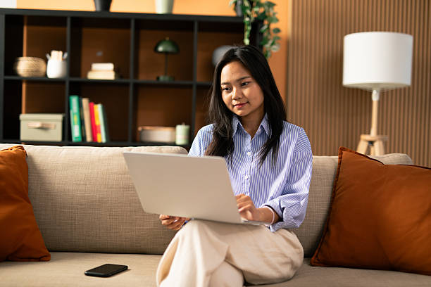istock Asian woman working on laptop from home couch 2248559502