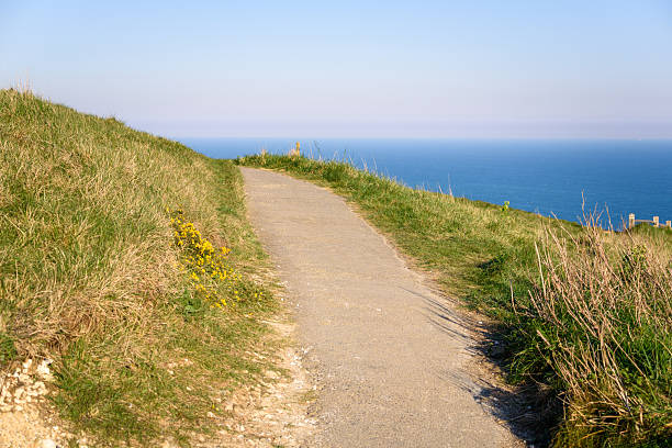 Aerial view, taken by drone, depicting a man walking on a country track leading down to the majestic Seven Sisters cliffs beyond at Cuckmere Haven in the south of England, UK.