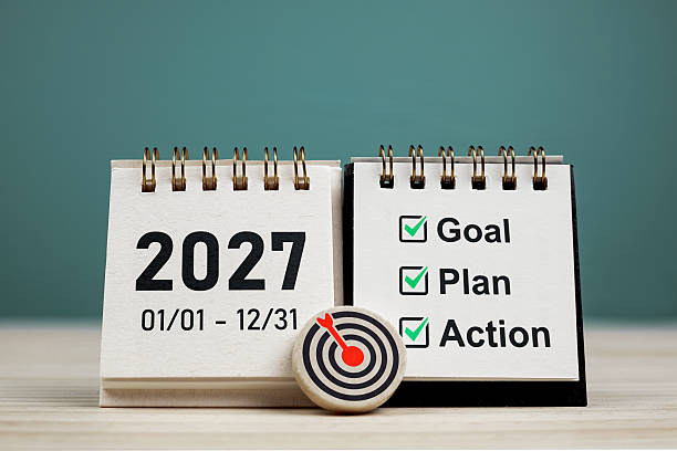istock Year 2027 on mini calendar page with check marks in words Goals, Plans, Actions and target icon on circle on wooden. 2248564199