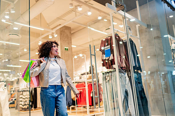 istock Young woman holding shooping bag and walking through the mall 2248565704