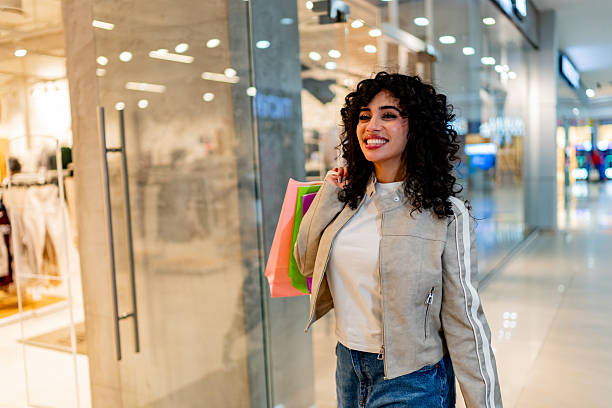 istock Young woman holding shooping bag and walking through the mall 2248565710
