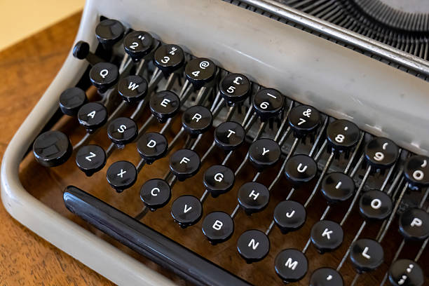 Vintage typewriter keyboard with round black keys, qwerty layout and shiny keytops on old writing machine, retro journalism and literature concept, close up detail of mechanical letters, numbers levers