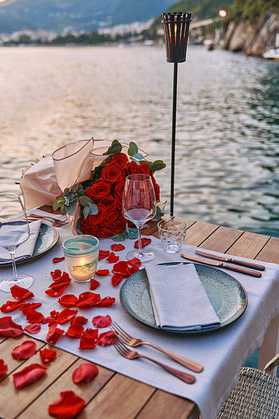 istock Romantic Dinner Setting by the Water with Red Roses, Candlelight, and Rose Petals Creating an Intimate Ambiance for a Memorable Evening 2248566522