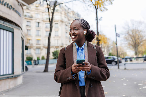 istock Young African woman smiling and using smartphone outdoors in an urban setting 2248571021