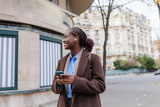 istock Young woman smiling and holding smartphone outdoors in urban setting 2248571047