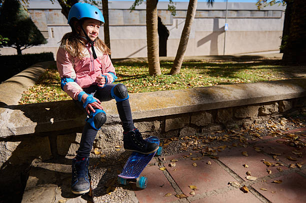 istock Young Girl Skating Outdoors With Helmet And Protective Gear On A Stone Wall 2248572241