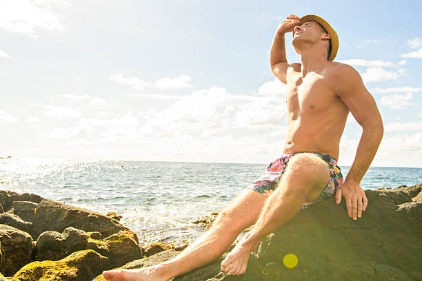 A swimsuit man standing on rocks at the beach