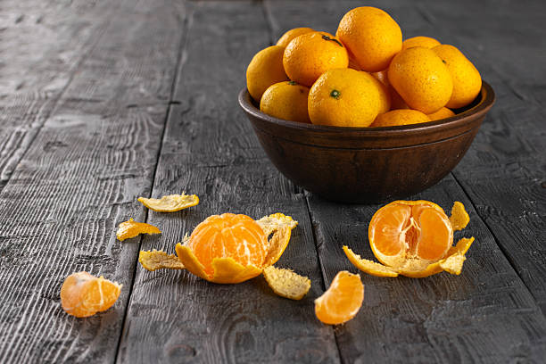 istock Fresh Tangerines in Rustic Wooden Bowl on Weathered Table with Peels 2248576036