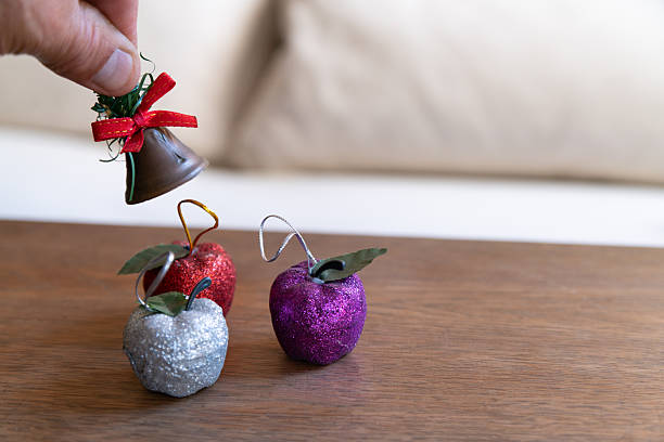 Woman holding up and placing Christmas ornaments on a large tree in her home, living room.