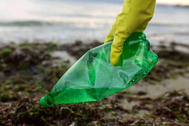 istock Volunteer picking up a green plastic bottle 2248580745