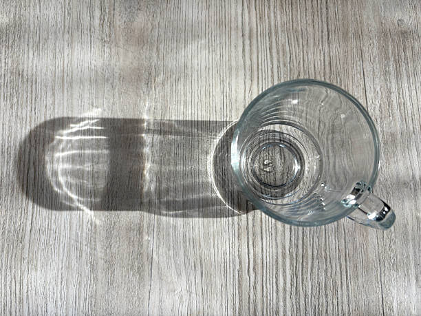 istock Empty drinking glass mug on the wood background with sunlight reflection and shadow 2248583312