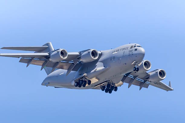 The image shows a Boeing C-17 Globemaster III doing a slow pass at the Bremerton Air Show.  The C-17 is a large military jet transport aircraft used primarily by the United States Air Force for both tactical and strategic airlift missions, mobilizing troops and cargo worldwide.   The aircraft is a critical component of the USAF Air Mobility Command.   This specific aircraft is based out of Joint Base Lewis-McChord (JBLM).  The photo was taken in July 2025 at the Bremerton Airport, Washington, USA
