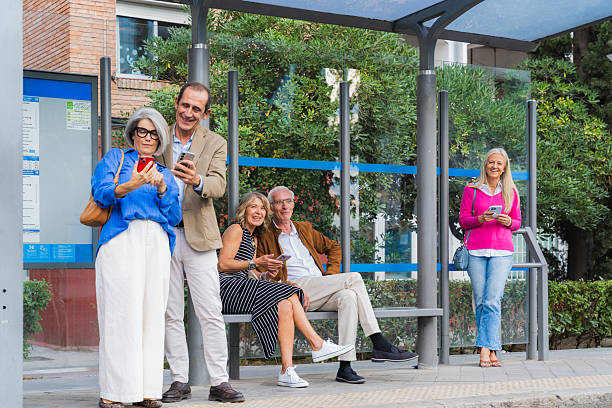 istock Mature friends using smartphones at bus stop together 2248584346