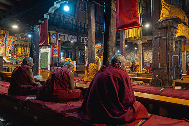 Leh ,India - May 18 , 2019 : An unidentified elderly woman turns a prayer wheel with her hands at the Shey Palace.Prayer wheels are cylindrical wheels on a rotating shaft made of metal, wood, leather on May 18 . 2019.
