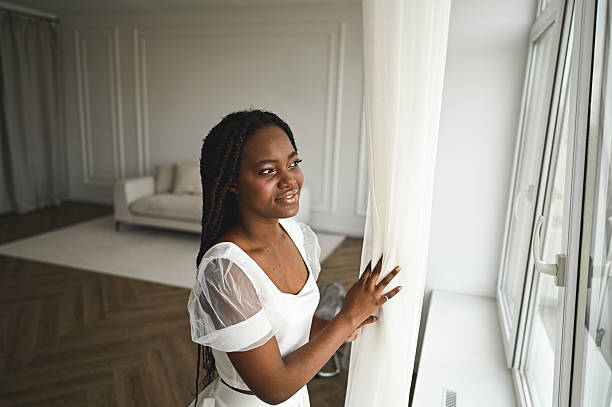 istock Black woman smiling looking out window feeling hopeful 2248585480