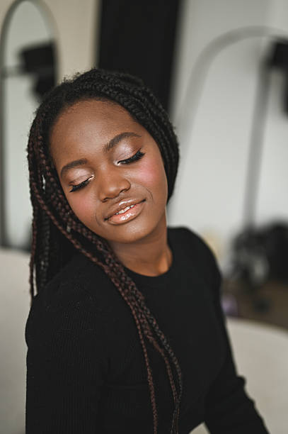 Young black woman with braids and subtle makeup closing eyes gracefully