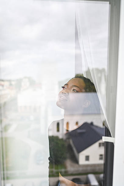 istock Young black woman looking up dreaming through window 2248586091