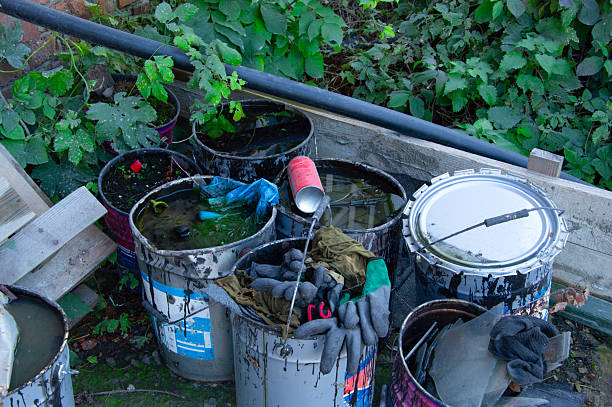 istock Various containers filled with liquid and debris are surrounded by overgrown vegetation, highlighting environmental neglect in an urban space 2248588633