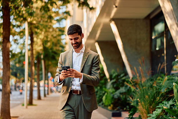 istock Happy businessman walking on street using smartphone 2248589417