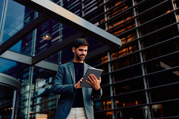 istock Young businessman using digital tablet outside modern office building 2248589518