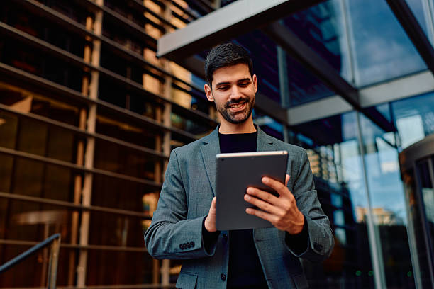 istock Businessman smiling using digital tablet outside modern office building 2248589553
