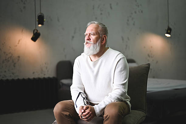 istock Senior man sitting contemplating in a modern indoor space 2248589993