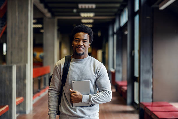 istock Young male student holding a tablet in university hallway 2248592454