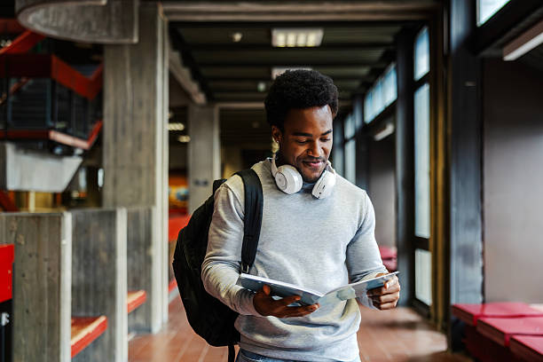 istock Young adult student reading book in university hallway 2248592627