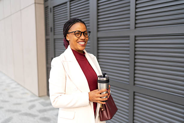 istock Businesswoman smiling while commuting with coffee in city 2248593076