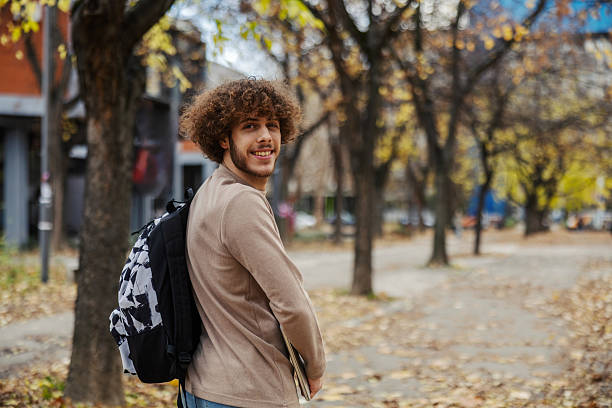 istock Young man smiling, walking in park during autumn 2248593109
