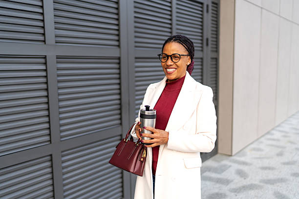 istock Professional woman smiling holding coffee outside office building 2248593110