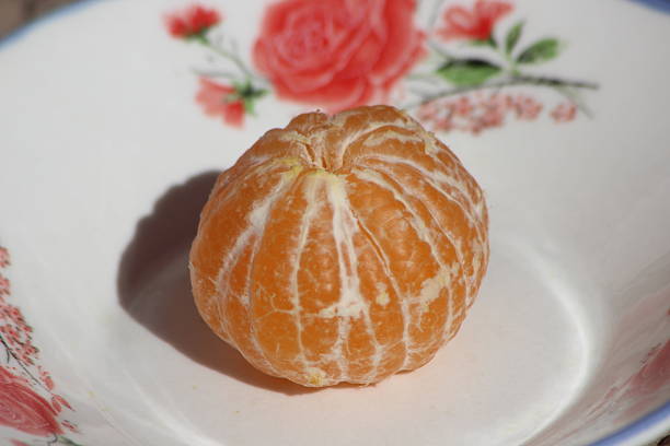 Three ripe orange tangerines with textured skin lie on a clean white background, creating a bright color accent.
