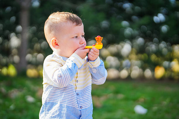 Toddler Playing with a Toy Bubble Pipe Outdoors