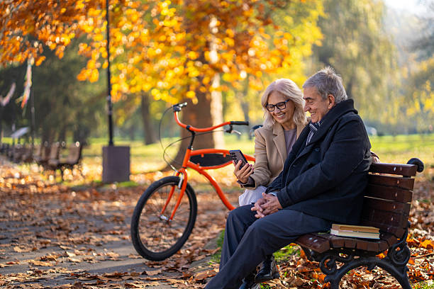 istock Senior couple relaxing on park bench using smartphone 2248606425