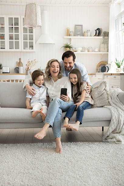 istock Happy mom dad two kids cuddle on couch using phone 2248607147