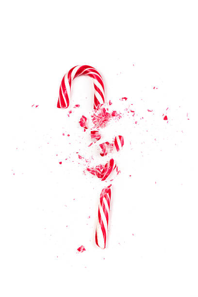 istock Candy cane explodes in a shower of red and white shards on a clean white surface, creating a festive holiday scene 2248607640