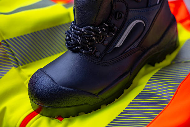 black heavy-duty work boots, strong yellow work jacket, vest, protective footwear, leather shoes with prominent reinforced steel toe, essential PPE for construction, safety equipment, hard labor