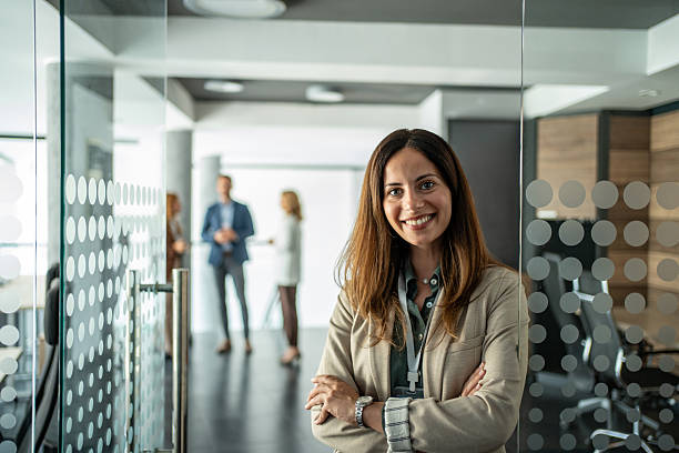 istock Confident businesswoman smiling in modern office hallway 2248620001