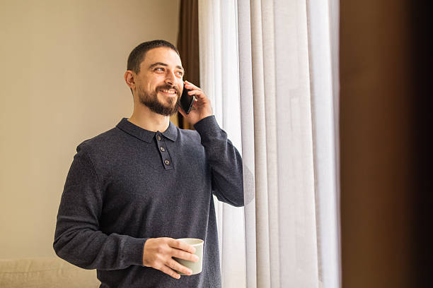 istock Handsome man with beard  using mobile phone and resting near the window at coffee time. 2248620725