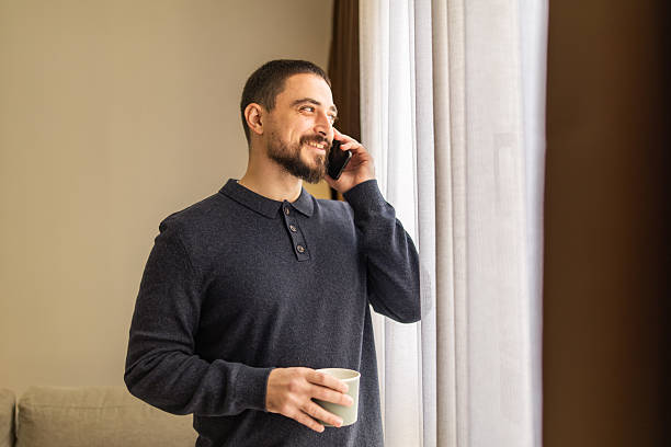 istock Handsome man with beard  using mobile phone and resting near the window at coffee time. 2248620793